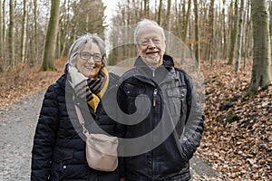 Active senior couple walking and smiling in autumn forest