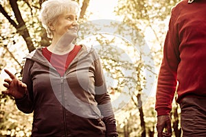 Active senior couple walking trough park and having conversation