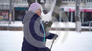 Active senior elderly woman training Nordic walking with trekking poles. Elderly woman practicing Nordic walking