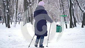 Active senior elderly woman training Nordic walking with trekking poles. Elderly woman practicing Nordic walking