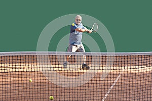 Active senior enjoy sports while playing tennis. Elderly tennis player playing ball on red clay court. healthy lifestyle photo