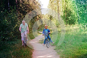 Active senior grandmother with kids riding bikes in nature