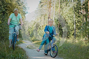 Active senior grandmother with kids riding bikes in nature