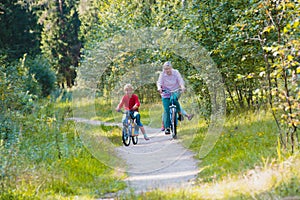 Active senior grandmother with kids riding bikes in nature