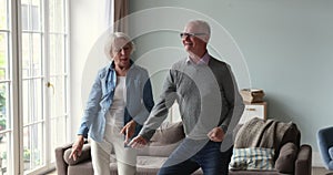 Active senior grey-haired spouses having fun dancing at home