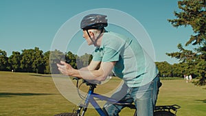 Active senior male cyclist on bike networking on smartphone outdoors