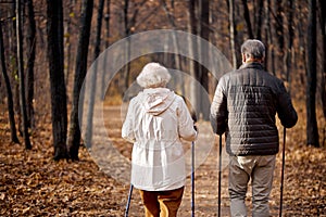 active senior male and female enjoying Nordic walking during hike in forest with husband