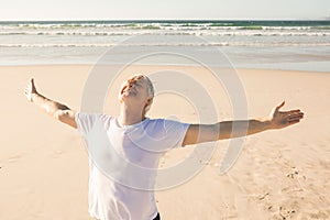 Active senior man with arms outstretched practicing yoga at beach