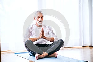 A contented senior man meditating at home.