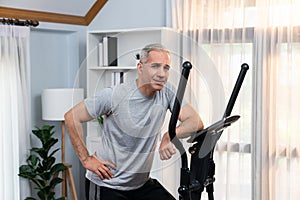 Active senior man running on elliptical running machine. Clout