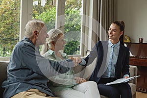 Active senior man shaking hands with real estate agent in living room