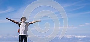 Active senior man standing and enjoying the top of the world opening arms and smiling - blue sky with clouds in background -