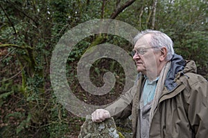 Active senior man thinking something over, outdoors in the woods