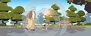 active senior man walking in park with his little dog grandfather relaxing with pet in urban park