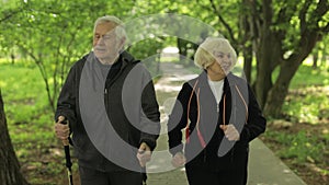 Active senior old couple. Man training Nordic walking, woman running in park