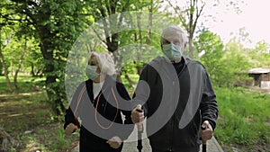 Active senior old man, woman training Nordic walking in park during quarantine