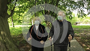 Active senior old man, woman training Nordic walking in park during quarantine