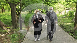 Active senior old man, woman training Nordic walking in park during quarantine