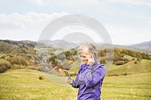 Active senior runner in nature with smart phone and earphones.