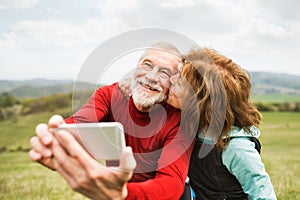 Aktivní starší běžci v přírodě fotografování pomocí chytrého telefonu.