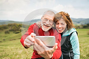 Active senior runners in nature taking photo with smart phone.