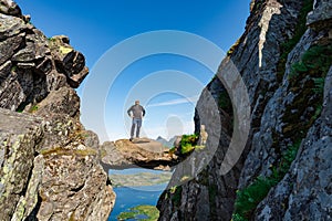Active Senior tourist man hiking at the beautiful Rock stuck in mountains Djevelporten. Norway