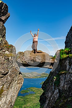 Active Senior tourist woman hiking at the beautiful Rock stuck in mountains Djevelporten. Norway