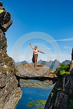 Active Senior tourist woman hiking at the beautiful Rock stuck in mountains Djevelporten. Norway