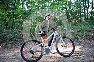 Active senior woman biker pushing ebike outdoors in forest. photo