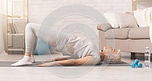 Active senior woman doing back exercise on floor at home