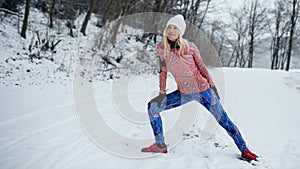 Active senior woman doing exercise outdoors in winter, stretching.