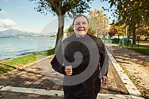 Active senior woman doing healthy exercises outdoors. Jogging