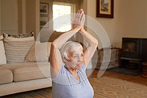 Active senior woman doing yoga in her living room photo