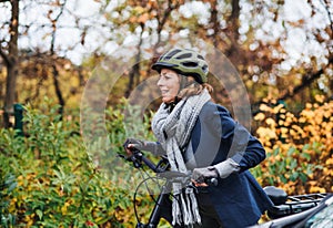 Active senior woman with electrobike cycling outdoors in park.