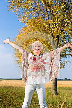 Active senior woman feeling free and happy while standing outdoo