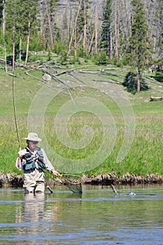 Active senior woman with fish leaping to net