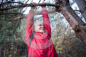 Active senior woman happy hanging from tree in forest