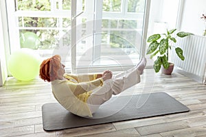 Active senior woman holding boat yoga pose