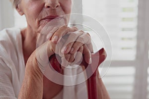 Active senior woman leaning on walking cane in a comfortable home