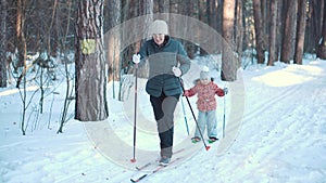 Active senior woman and little girl. Cross country skiing in the forest.