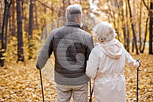 active senior woman and man enjoying Nordic walking during hike in forest with husband