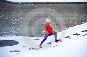 Active senior woman outdoors in snowy winter, doing exercise.
