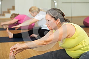 Active senior woman practicing yoga at group