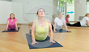 Active senior woman practicing yoga at group