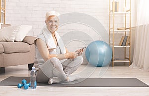 Active senior woman resting with cellphone after workout