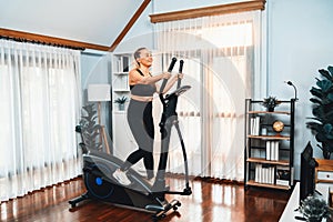 Active senior woman running on elliptical running machine. Clout