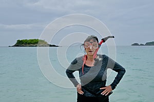 Active Senior Woman With Snorkel Gear Standing in Tropical Bay