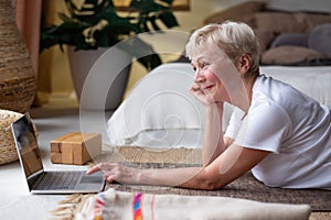 Active senior woman surfing in internet on yoga mat
