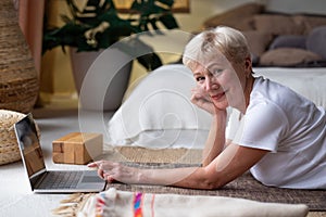 Active senior woman surfing in internet on yoga mat