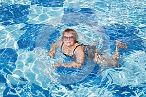 Active senior woman swimming in blue pool water